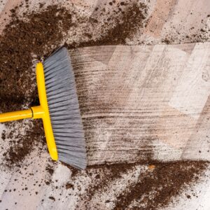 Close-up top view of broom sweeping floor with soil