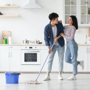 Loving asian couple mopping floor in kitchen