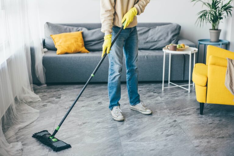 Man washes the floors with a mop in room.