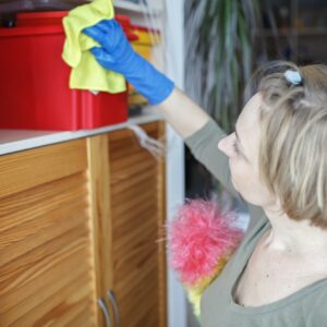 Woman cleans home with vacuum cleaner, wipes dust from the shelves, washes window