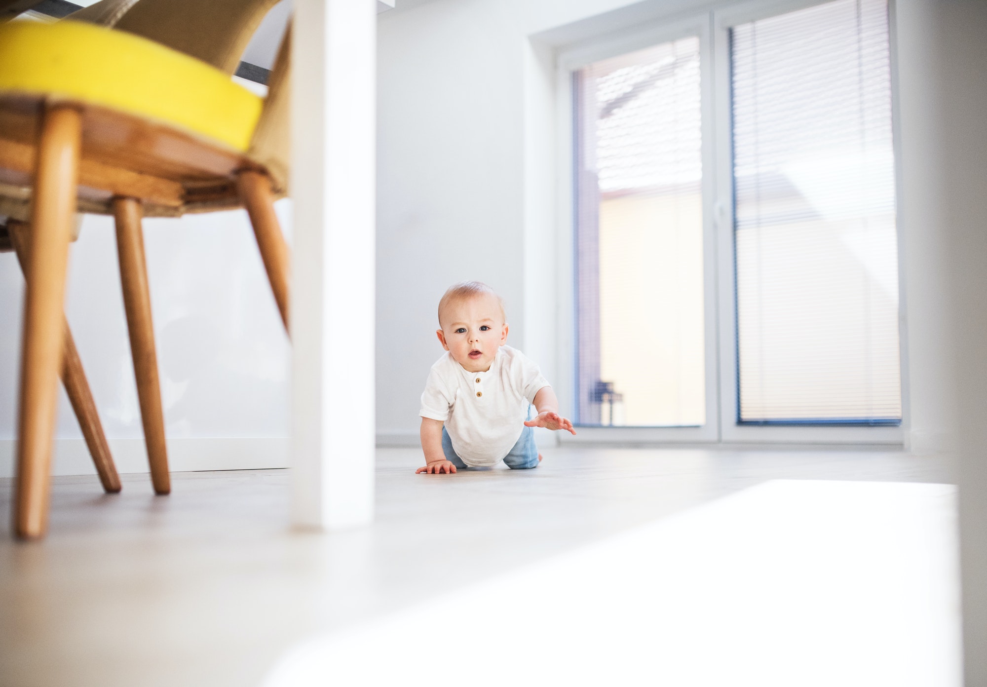 A baby boy crawling on the floor at home.