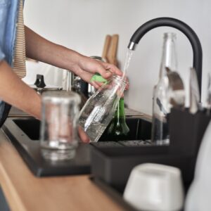 Woman washing white glass bottles for recycling